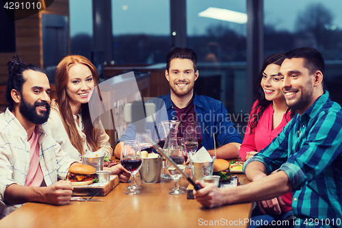 Image of friends taking selfie by smartphone at restaurant