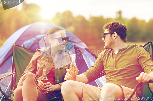 Image of happy couple drinking beer at campsite tent