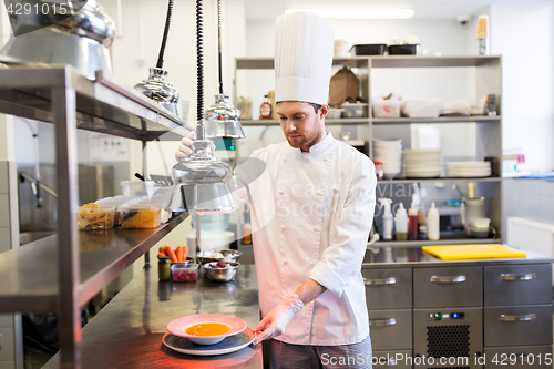 Image of happy male chef cooking food at restaurant kitchen