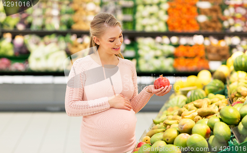 Image of happy pregnant woman with pomegranate at grocery