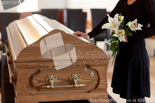 Image of woman with lily flowers and coffin at funeral