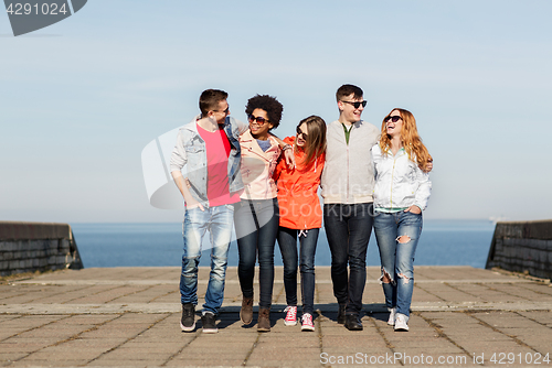 Image of happy teenage friends in shades talking on street