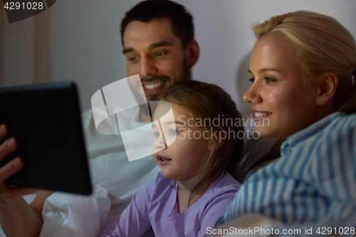 Image of happy family with tablet pc in bed at home