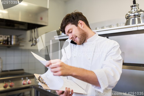 Image of chef cook calling on smartphone at restaurant kitchen