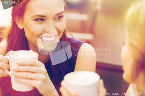 Image of smiling young women with coffee cups at cafe