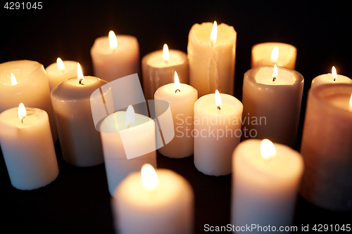 Image of candles burning in darkness over black background