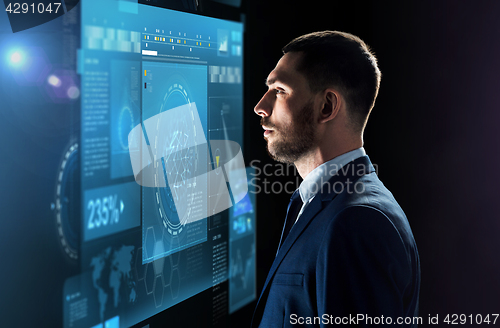 Image of businessman looking at virtual screen over black