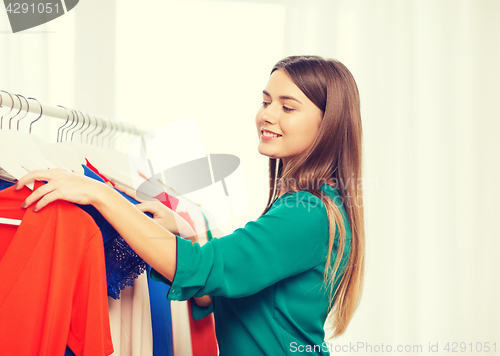 Image of happy woman choosing clothes at home wardrobe