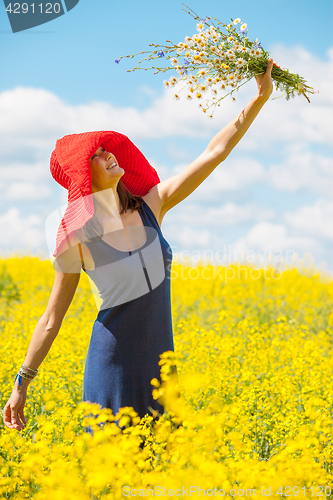 Image of joyful woman in a red hat with a bouquet of wild flowers