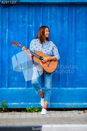 Image of Beautiful smiling woman in jeans playing guitar 