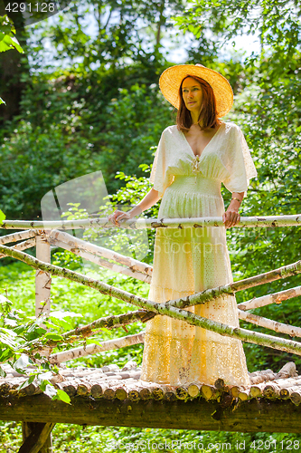 Image of Beautiful woman in a white summer dress and a straw hat stands o