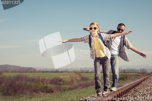 Image of Father and daughter walking on the railway at the day time.