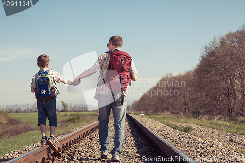 Image of Father and son walking on the railway at the day time.