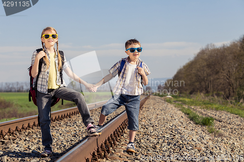 Image of Happy brother and sister walking on the railway at the day time.