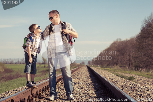 Image of Father and son walking on the railway at the day time.