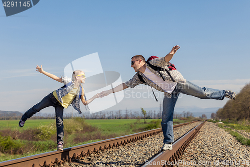 Image of Father and daughter walking on the railway at the day time.