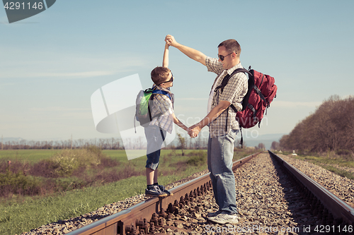 Image of Father and son walking on the railway at the day time.