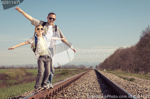 Image of Father and daughter walking on the railway at the day time.