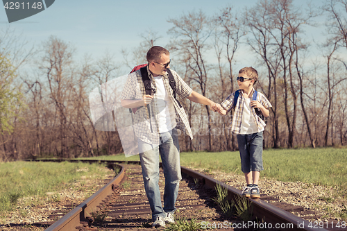 Image of Father and son walking on the railway at the day time.