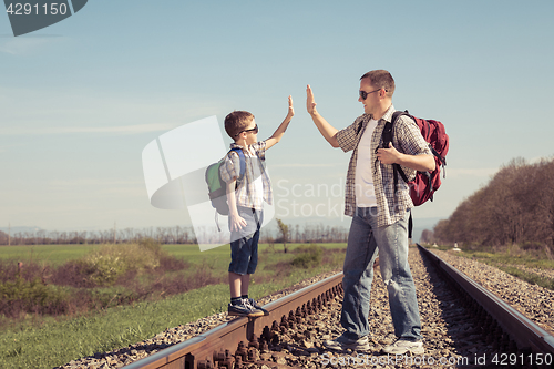 Image of Father and son walking on the railway at the day time.