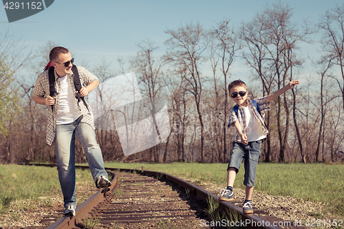 Image of Father and son walking on the railway at the day time.