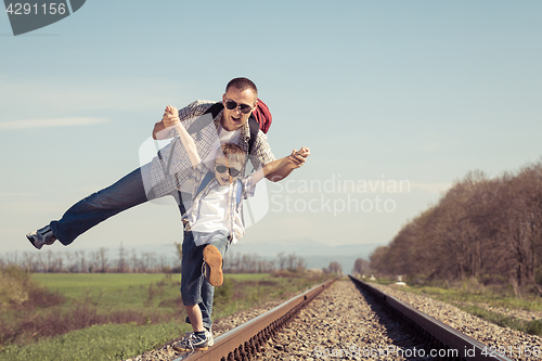 Image of Father and son walking on the railway at the day time.