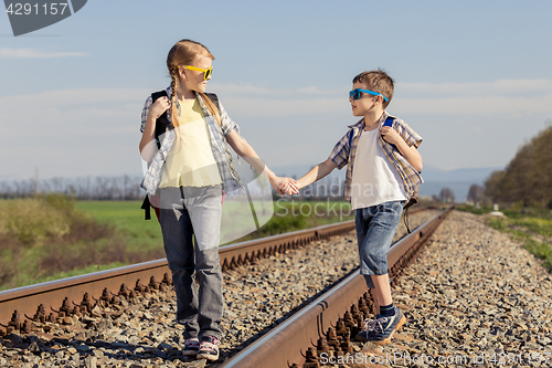 Image of Happy brother and sister walking on the railway at the day time.