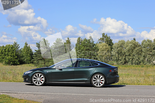 Image of Metallic Green Tesla Model S on Summer Road