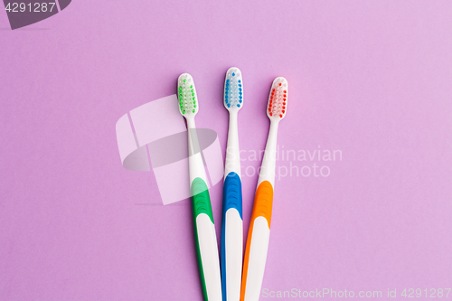 Image of Photo of three multi-colored toothbrushes