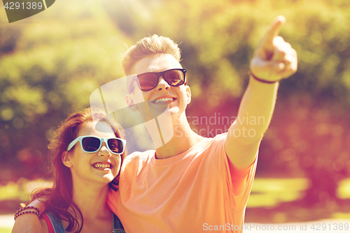 Image of happy couple pointing finger at summer park