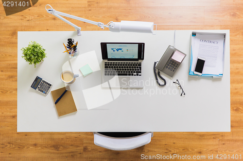 Image of laptop, phone and other office stuff on table