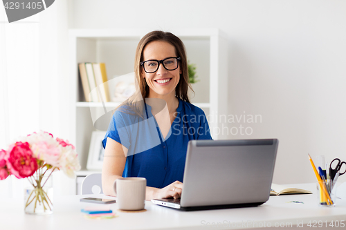 Image of happy woman with laptop working at home or office