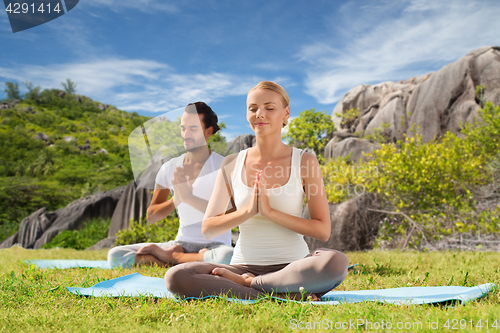 Image of happy couple doing yoga and meditating outdoors