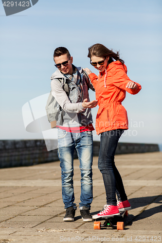 Image of happy couple with longboard riding outdoors