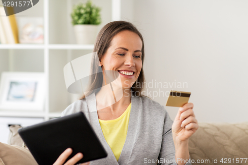 Image of happy woman with tablet pc and bank card at home