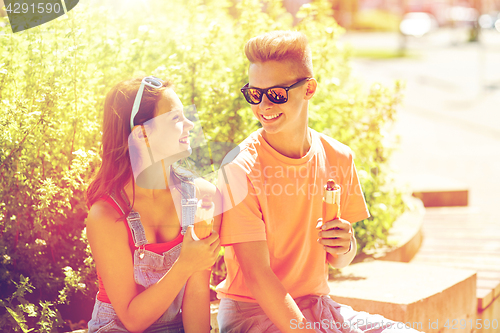 Image of happy teenage couple eating hot dogs in city