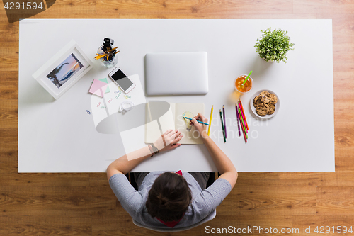 Image of woman drawing in notebook at home office