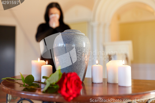 Image of cremation urn and woman crying in church