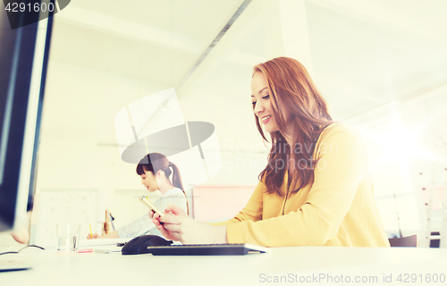 Image of businesswoman texting on smartphone at office