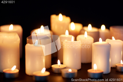 Image of candles burning in darkness over black background