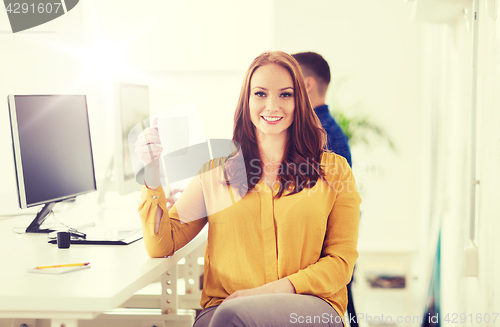 Image of happy woman drinking coffee or tea at office