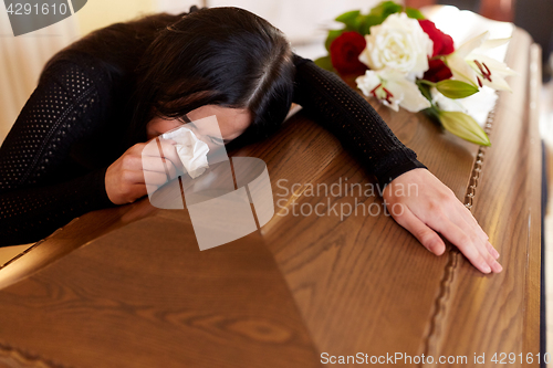 Image of woman with coffin crying at funeral in church