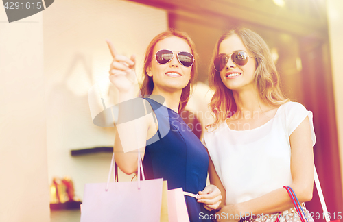 Image of happy young women with shopping bags in mall