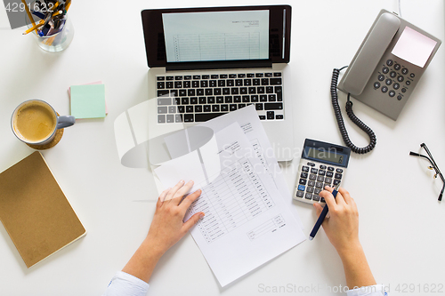 Image of hands with calculator and papers at office table