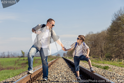 Image of Father and son walking on the railway at the day time.