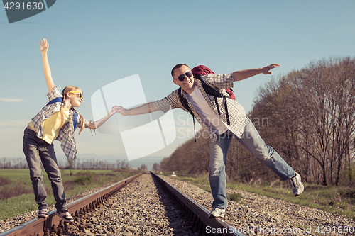 Image of Father and daughter walking on the railway at the day time.