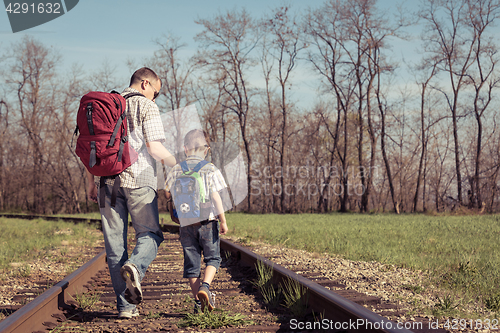 Image of Father and son walking on the railway at the day time.