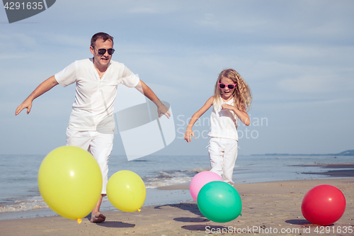 Image of Father and daughter  playing with balloons on the beach at the d