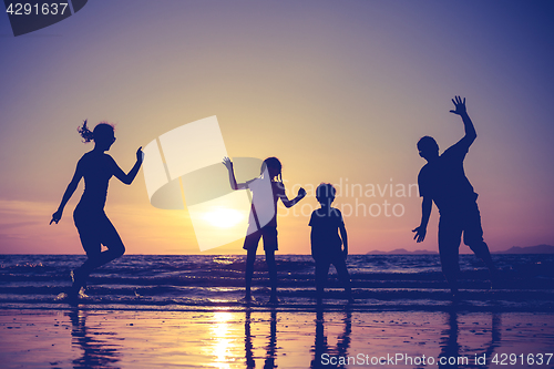 Image of Silhouette of happy family who playing on the beach at the sunse