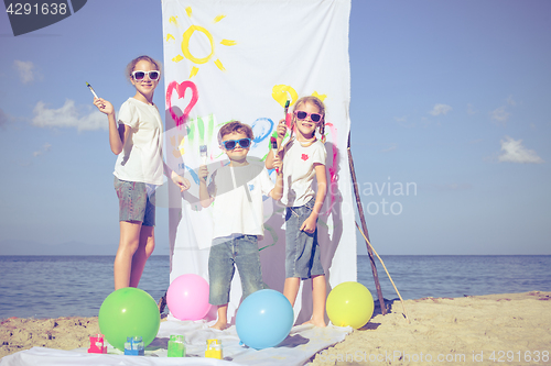 Image of Two sisters and brother playing on the beach at the day time.